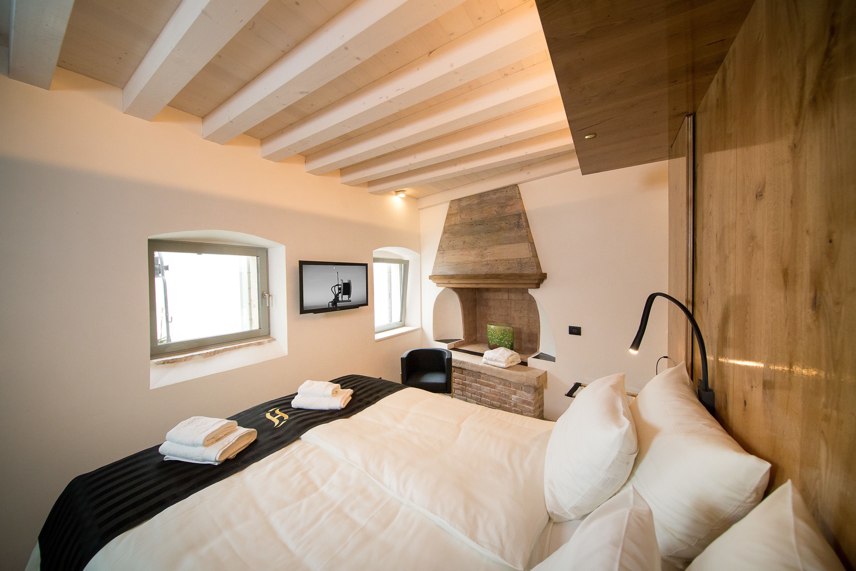 Ein Schlafzimmer mit Bett, Sessel, Kamin und Fenster.