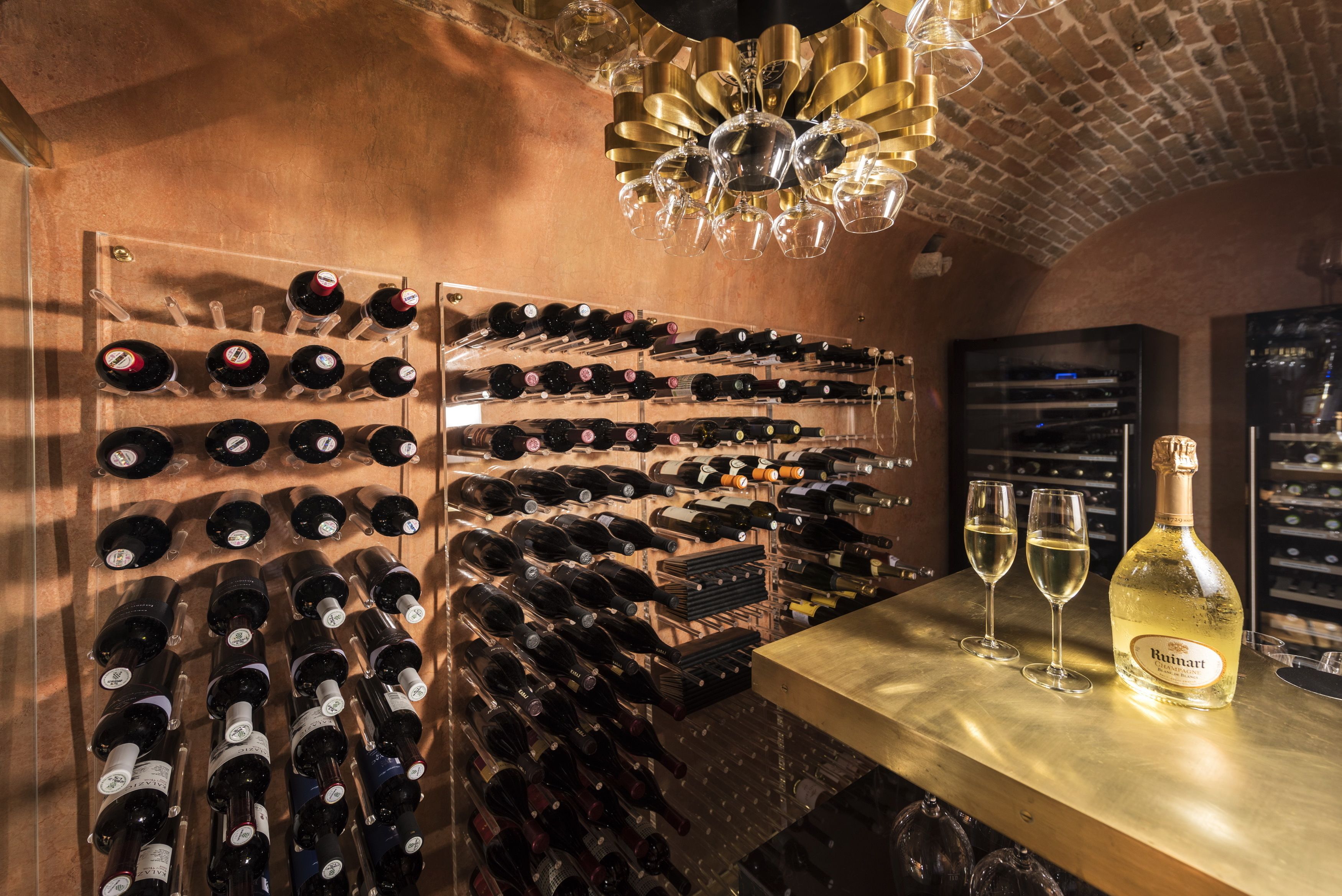 A wine cellar with numerous wine bottles on racks and two glasses on a counter.
