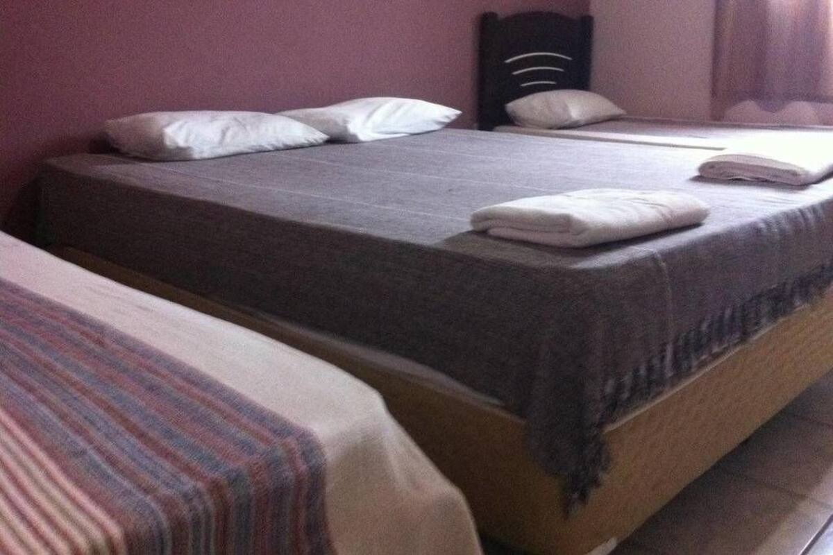 A hotel room with two single beds, each with a striped bedspread and white pillows.