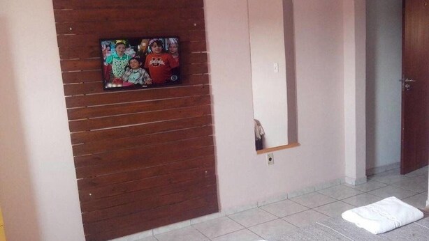 A room with a wooden panel wall, a mirror, and two white towels on the floor. - Hotel 50 (Extrema)
