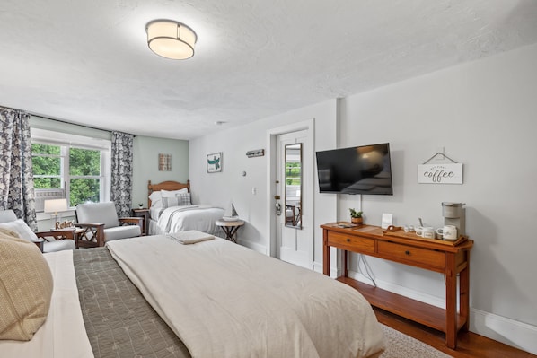 A hotel room with two beds, a TV, a coffee station, and a view of the outdoors. - Inn On Golden Pond (Holderness)