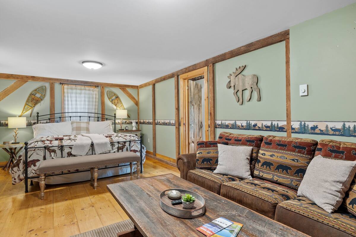 A cozy room with a bed, a bench, a sofa, and a wooden table.