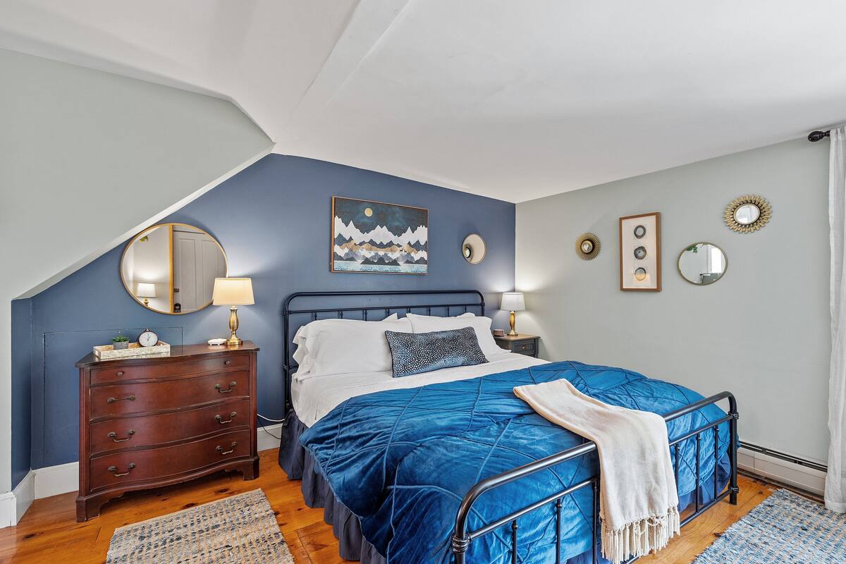 A bedroom with a bed, dresser, and artwork on the wall.