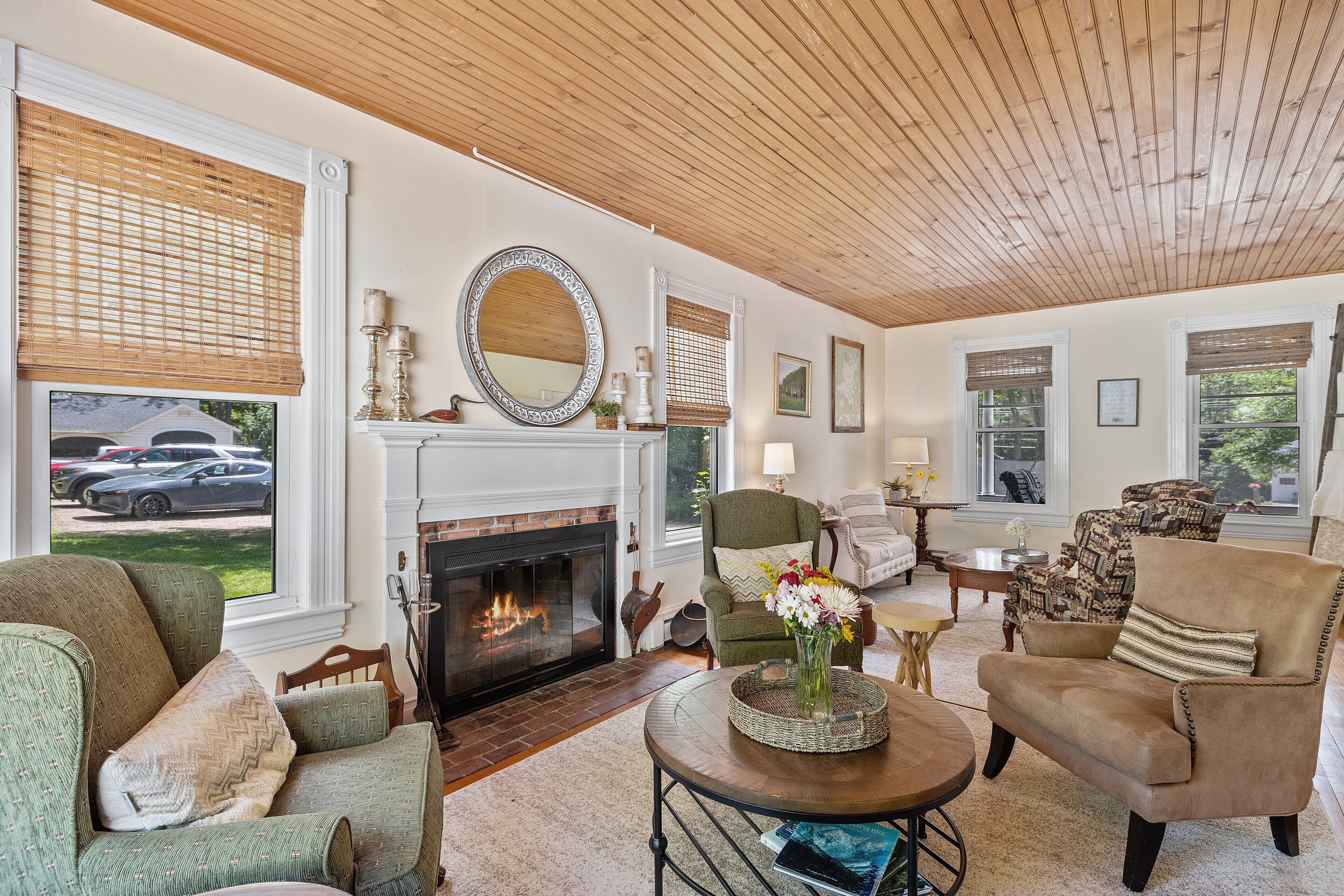 A cozy living room with a fireplace, comfortable seating, and a view of the outside.