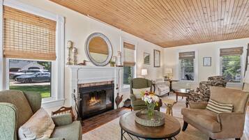 A cozy living room with a fireplace, comfortable seating, and a view of the outside.