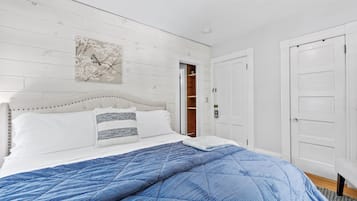 A bedroom with a bed, a white door, and a wooden wall.