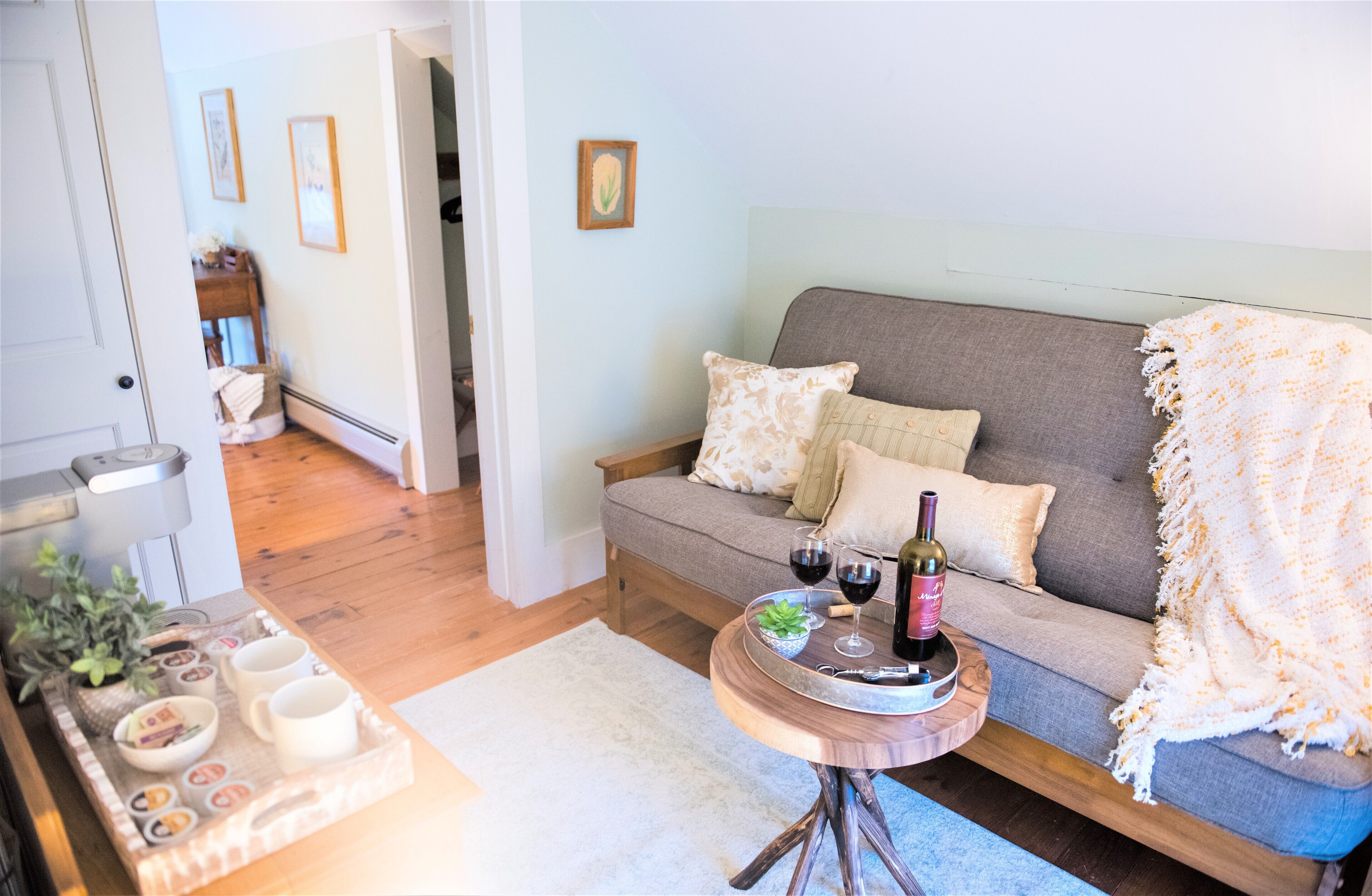 A cozy living room with a sofa, a coffee table, and a tray with cups and a bottle.