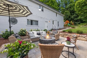 Eine Terrasse mit Gartenmöbeln, einem Feuerkorb und einer Schaukel.