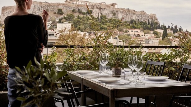 Une table dressée pour le dîner, avec en arrière-plan une vue sur d’anciennes ruines.