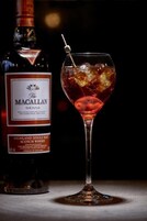 Egy üveg The Macallan Sienna whisky, egy pohár jégkockákkal és egy szívószállal.