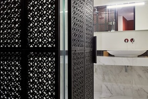 Uma casa de banho moderna com uma pia branca, dois espelhos redondos e um painel decorativo em preto e branco.