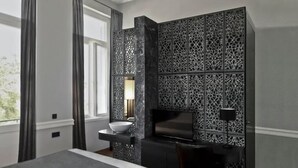 Une chambre d’hôtel moderne dotée d’un grand lit, d’un bureau avec un ordinateur, d’une télévision et d’une salle de bain avec un lavabo.