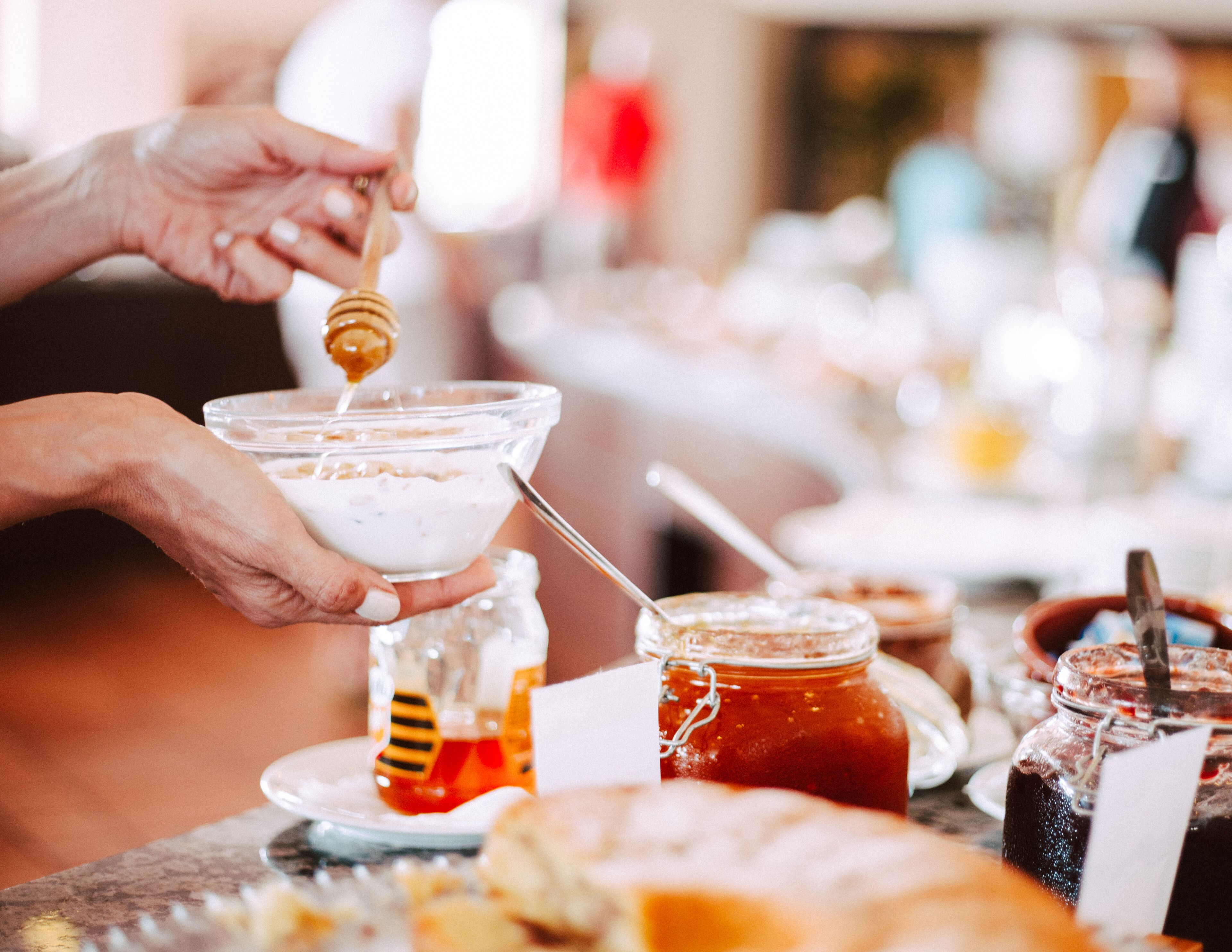A person pouring honey into a bowl of yogurt.