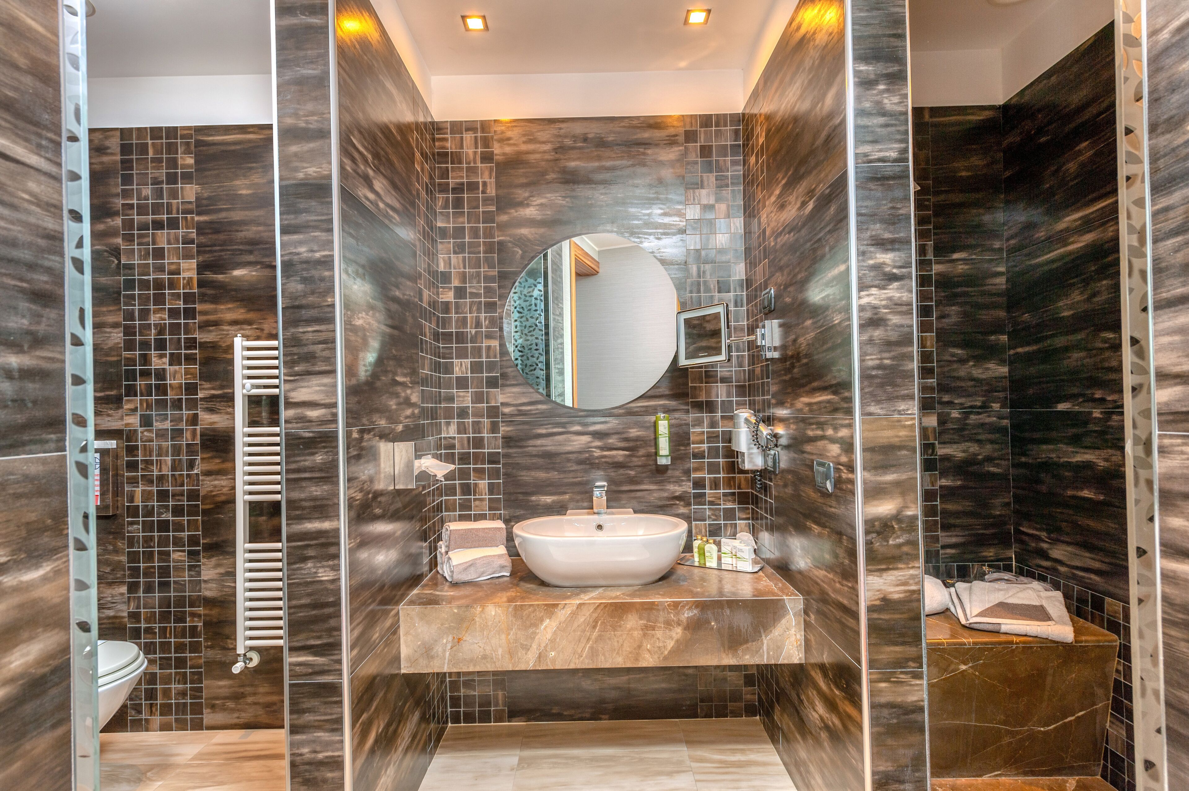 A modern bathroom with a large sink, mirror, and towel rack.