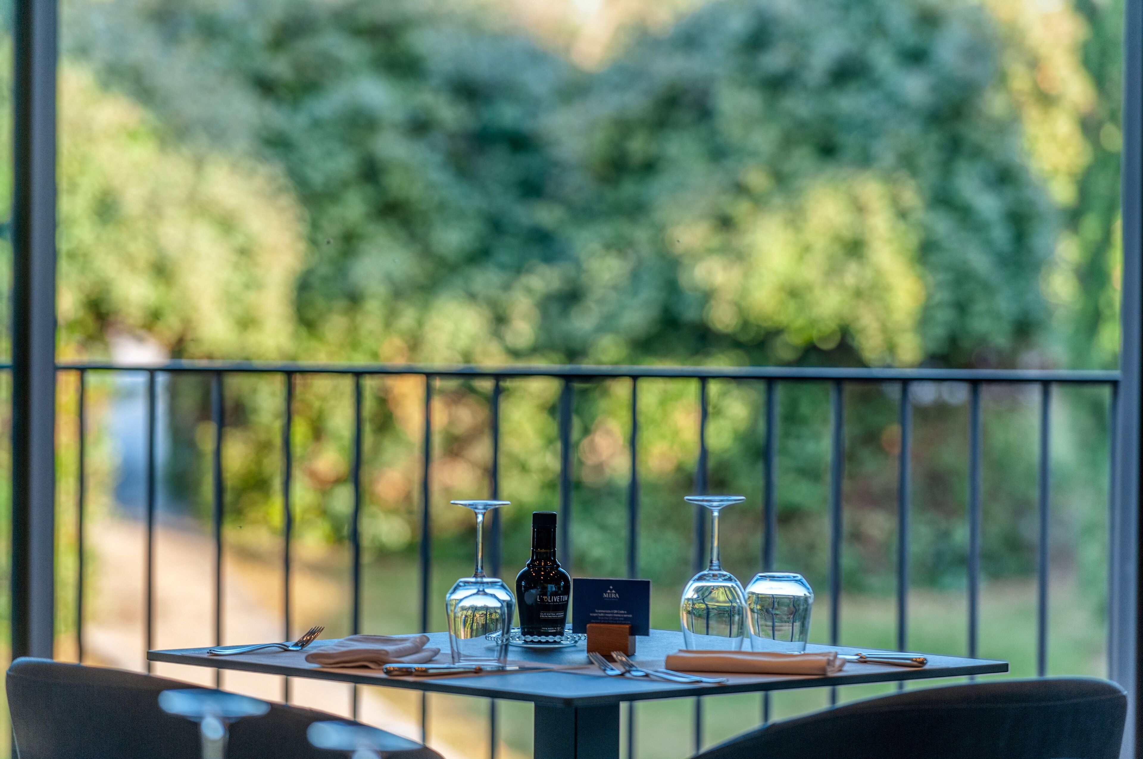 A table set outdoors with wine glasses, a bottle, and a menu.