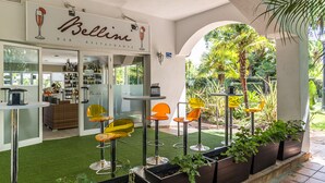 An outdoor seating area with bar stools and planters, a bar with shelves of bottles, and a sign for 'Bellini Bar Restaurante'. - Puerto Banús Luxury Penthouse (Marbella)