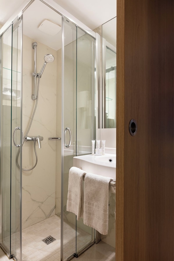 A modern bathroom with a glass-enclosed shower, a white sink, and a mirror.