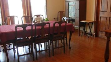 A dining area with a wooden table and chairs, a red tablecloth, and a cabinet.