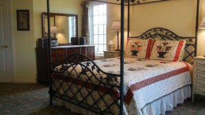 Un dormitorio con una cama con dosel, un aparador, un espejo y una ventana con cortinas.