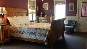 A bedroom with a wooden bed, a nightstand, a dresser, a chair, and a door with a window.