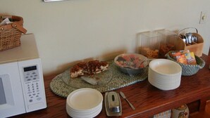 Una encimera de cocina con microondas, platos, tazones y un tostador.