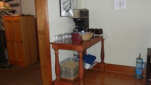 Una mesa de madera con una cafetera, vasos y una cesta.