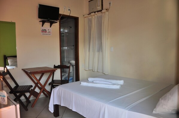 A hotel room with a bed, a small table, a chair, a television, and a curtain. - Pousada Cores do Mar (Paraty)