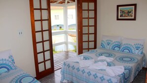 Quarto com cama, uma cadeira e porta que dá para área externa.