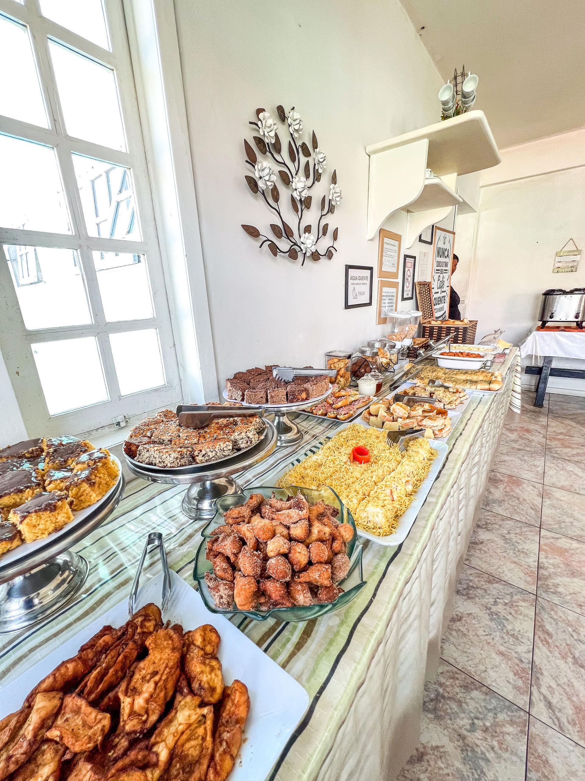 Buffet com diversos alimentos, um detalhe decorativo na parede e um aviso sobre a disponibilidade de água.