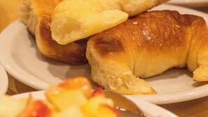 A table with plates of food including croissants and fruit. - Hotel Bariloche By Tierra Gaucha (San Carlos de Bariloche)