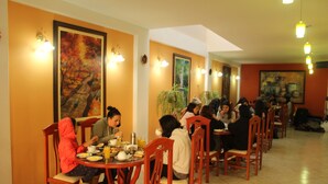 Un restaurante con sillas y mesas de madera, donde personas están cenando.