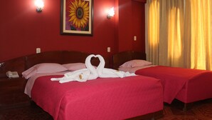 Habitación de hotel con dos camas, paredes rojas, un cuadro de un girasol y una cortina amarilla.