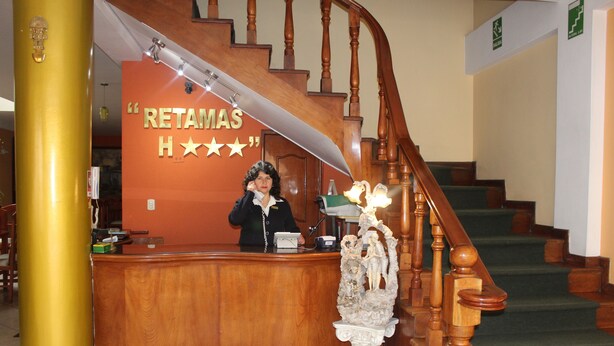 Una recepción con un letrero que dice "RETAMAS H***" y una escalera con barandillas de madera.