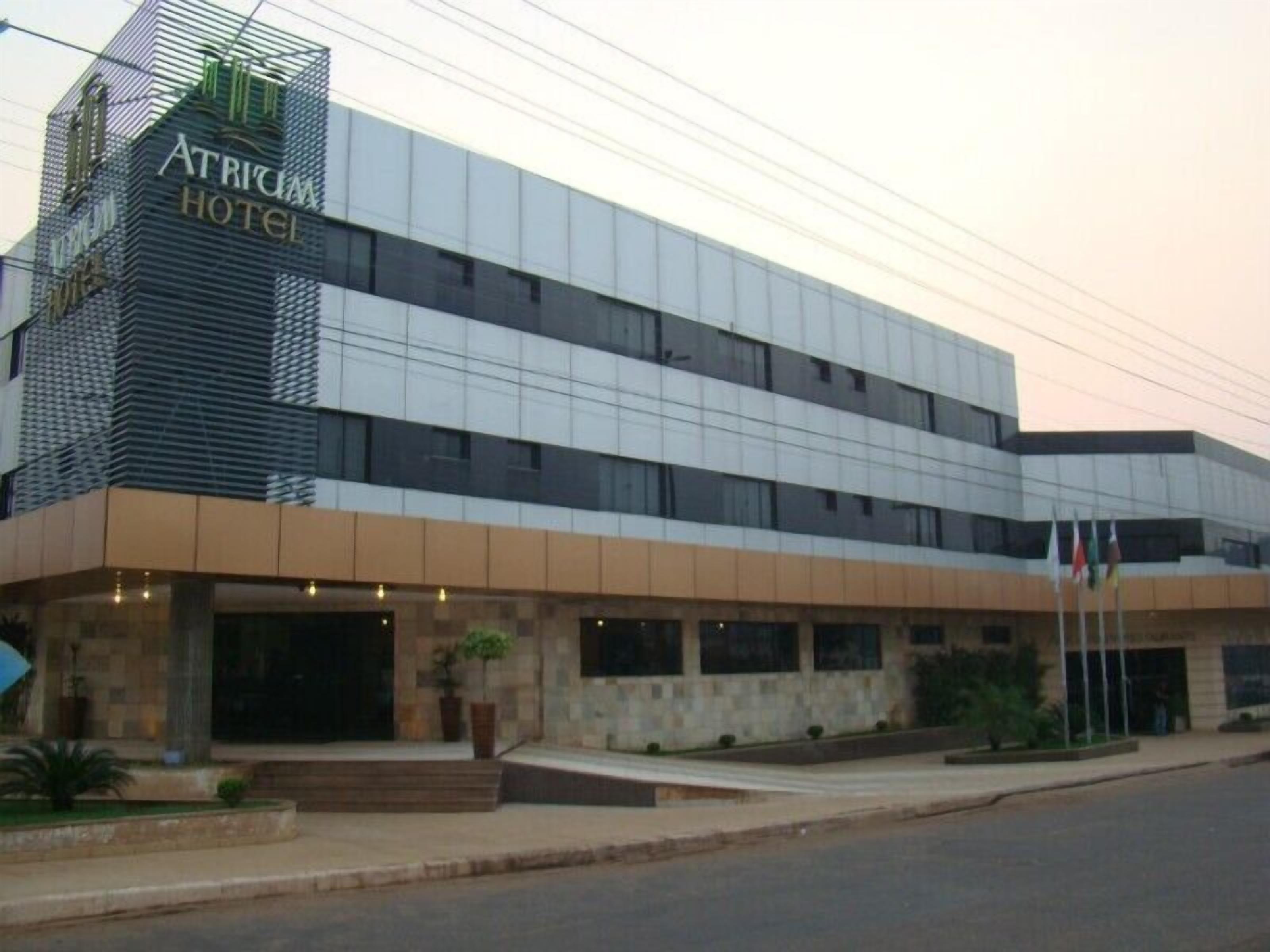 Il s’agit d’un hôtel moderne, reconnaissable à son enseigne bien visible indiquant « Atrium Hotel ». Il se distingue par son architecture à plusieurs étages, sa façade en verre, son toit plat et une série de fenêtres.