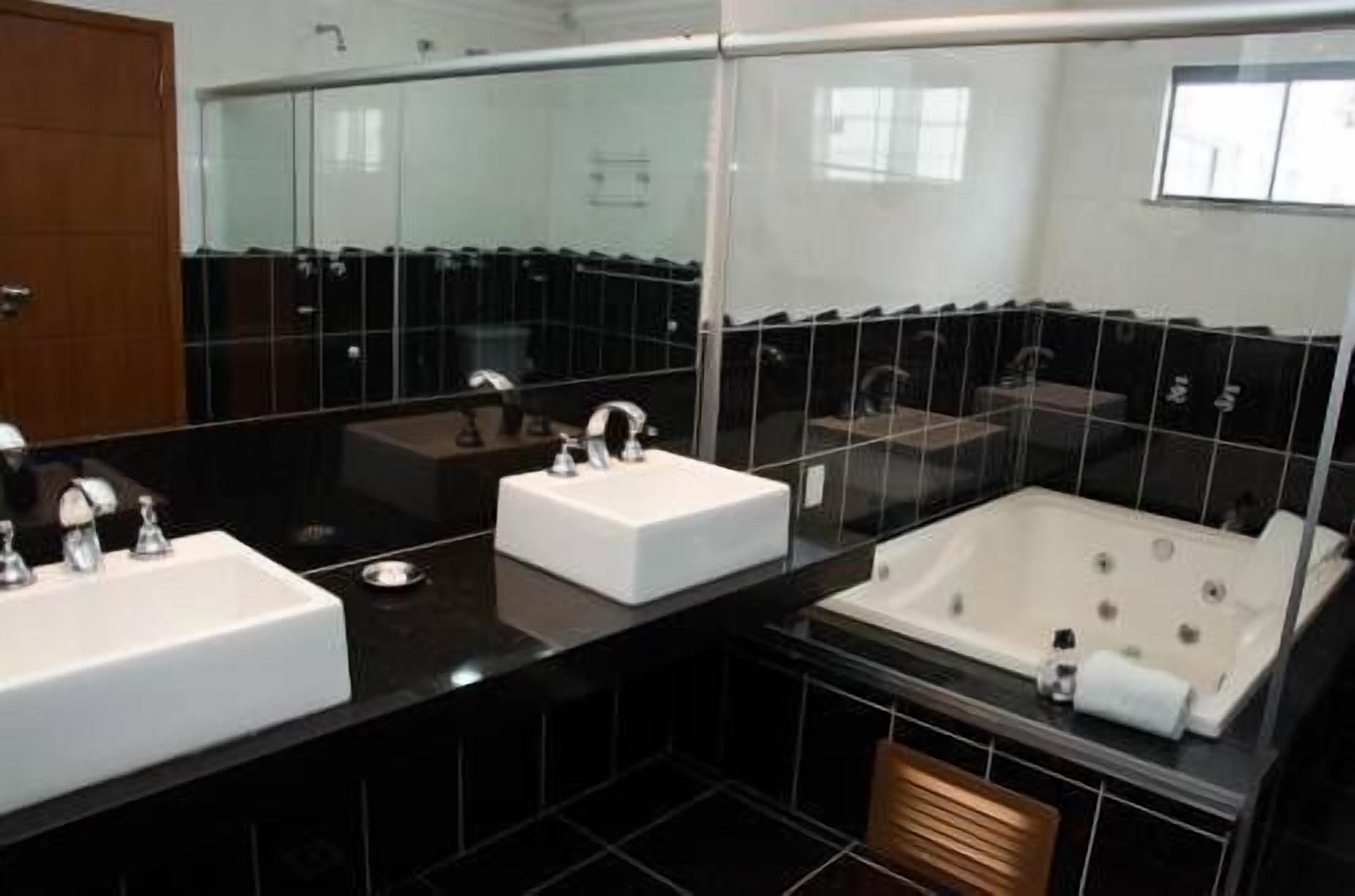 Un baño moderno con dos lavamanos, una bañera y un espejo grande.