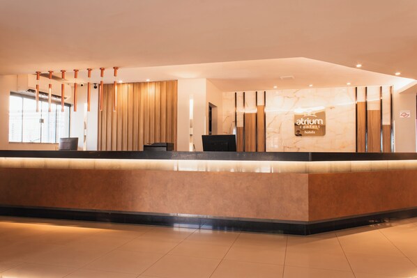 A reception desk with a marble wall and a sign that reads "Atrium Comfort Hotels". - Atrium Confort Hotel Parauapebas (Parauapebas)