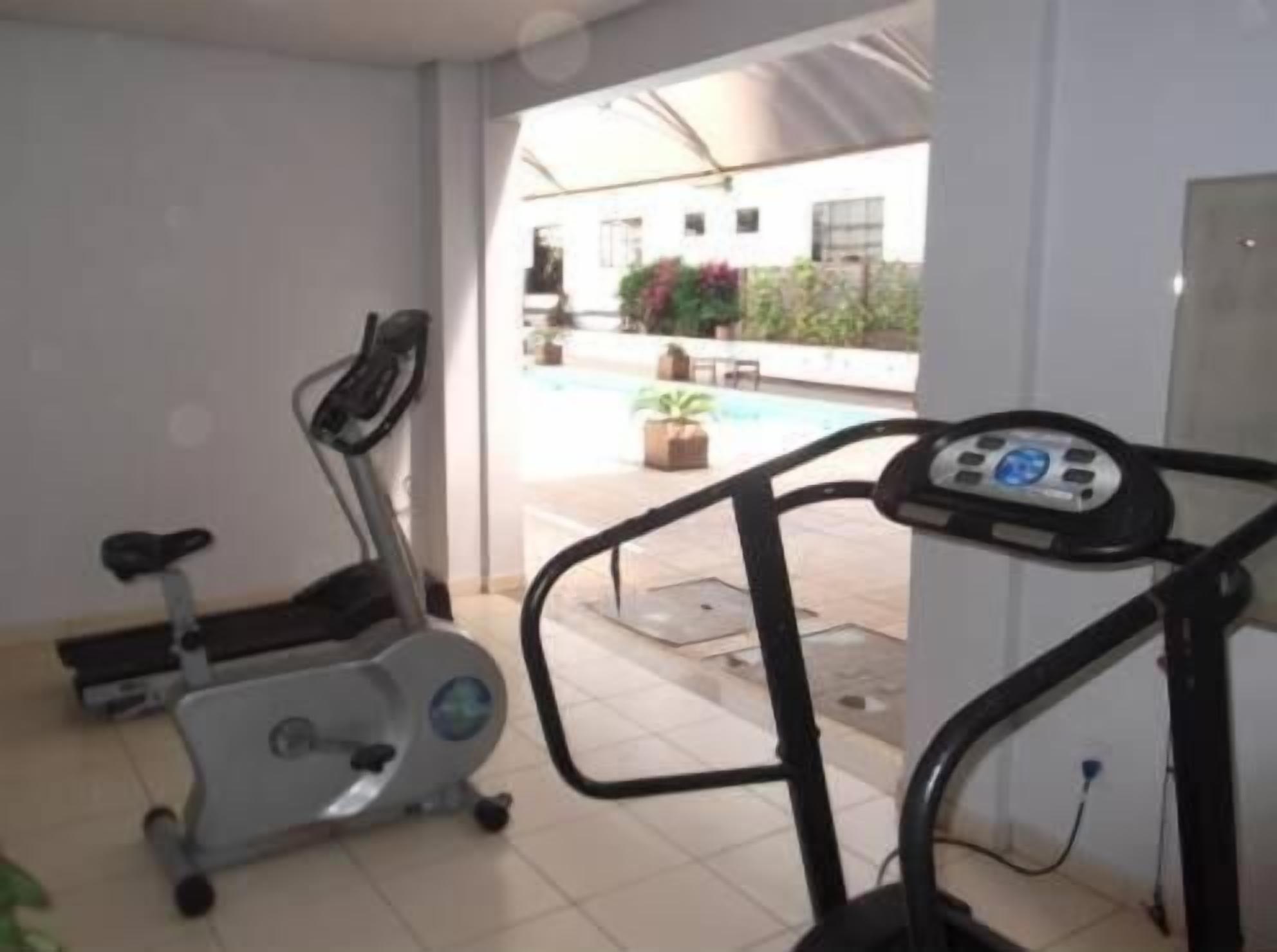 A home gym with two stationary bikes and a treadmill.