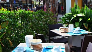 An outdoor café with tables set for two, each with a white cup, saucer, and a small bowl. - Hotel Dante (Jesolo)