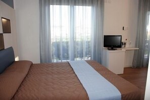 A hotel room with a bed, a television, and a small desk with a cup and a glass. - Hotel Dante (Jesolo)