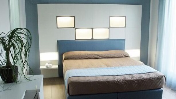 A modern bedroom with a bed, bedside tables, and a potted plant. - Hotel Dante (Jesolo)