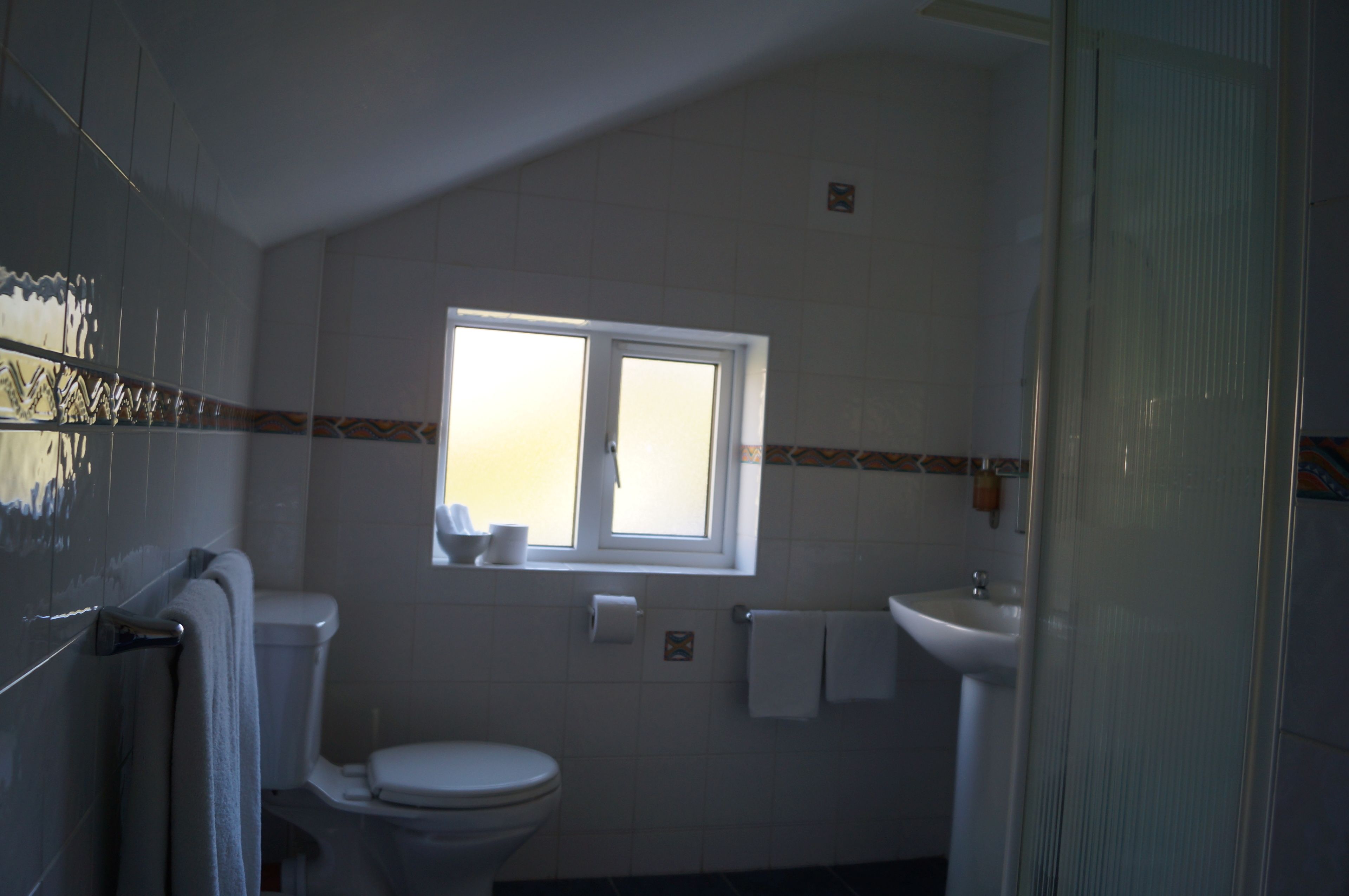 A bathroom with a toilet, sink, and window.