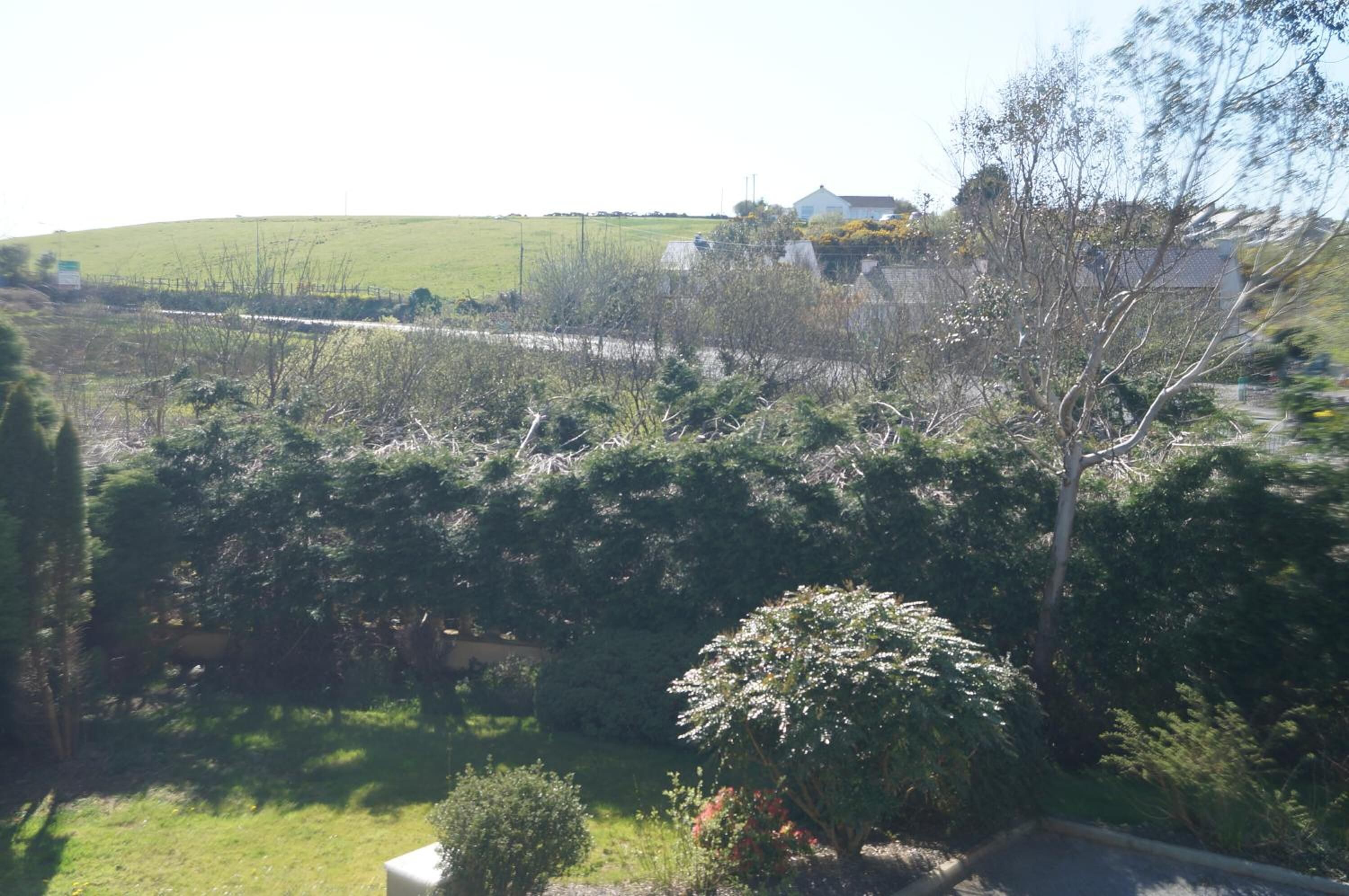 A rural landscape with a house, a fence, and a road.