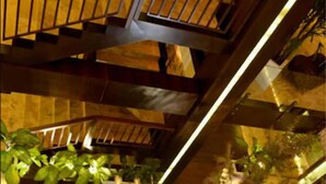 An indoor space with wooden flooring, yellow seating, and potted plants.