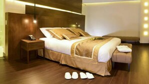 A modern hotel room with a large bed, a bedside table, and a nightstand.