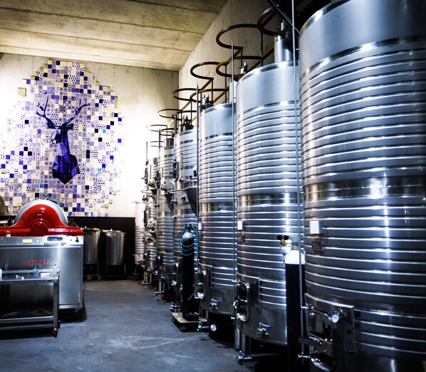A brewery with stainless steel tanks and a tiled wall with a deer mosaic. - Herdade da Rocha Boutique Lodge (Crato)