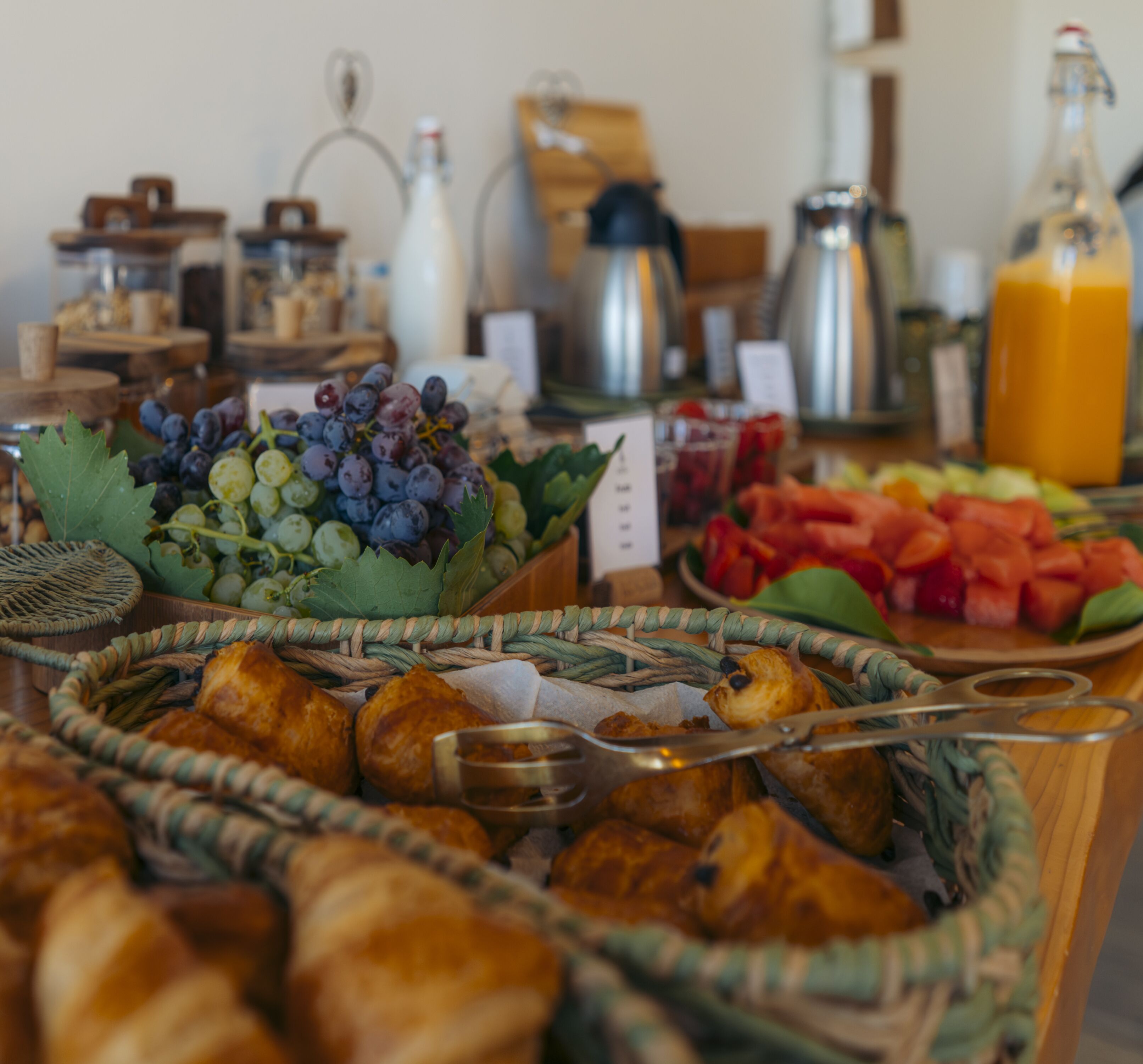A buffet with various food items including bread, fruits, and beverages.