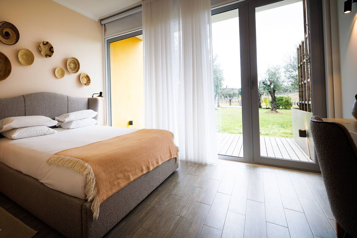 A bedroom with a bed, a view of the outdoors, and a balcony.