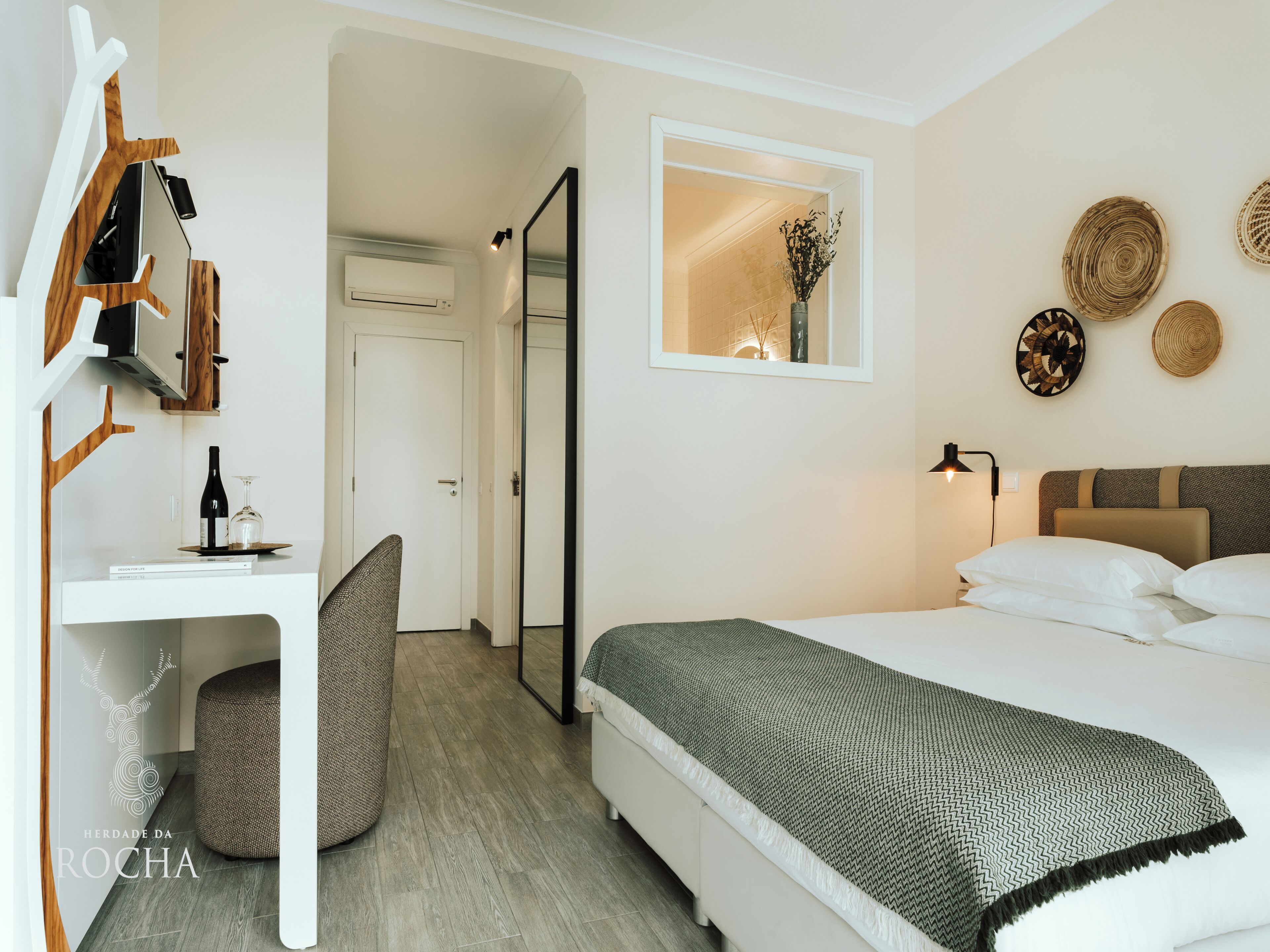 Un dormitorio moderno con cama, mesita de noche y espejo.