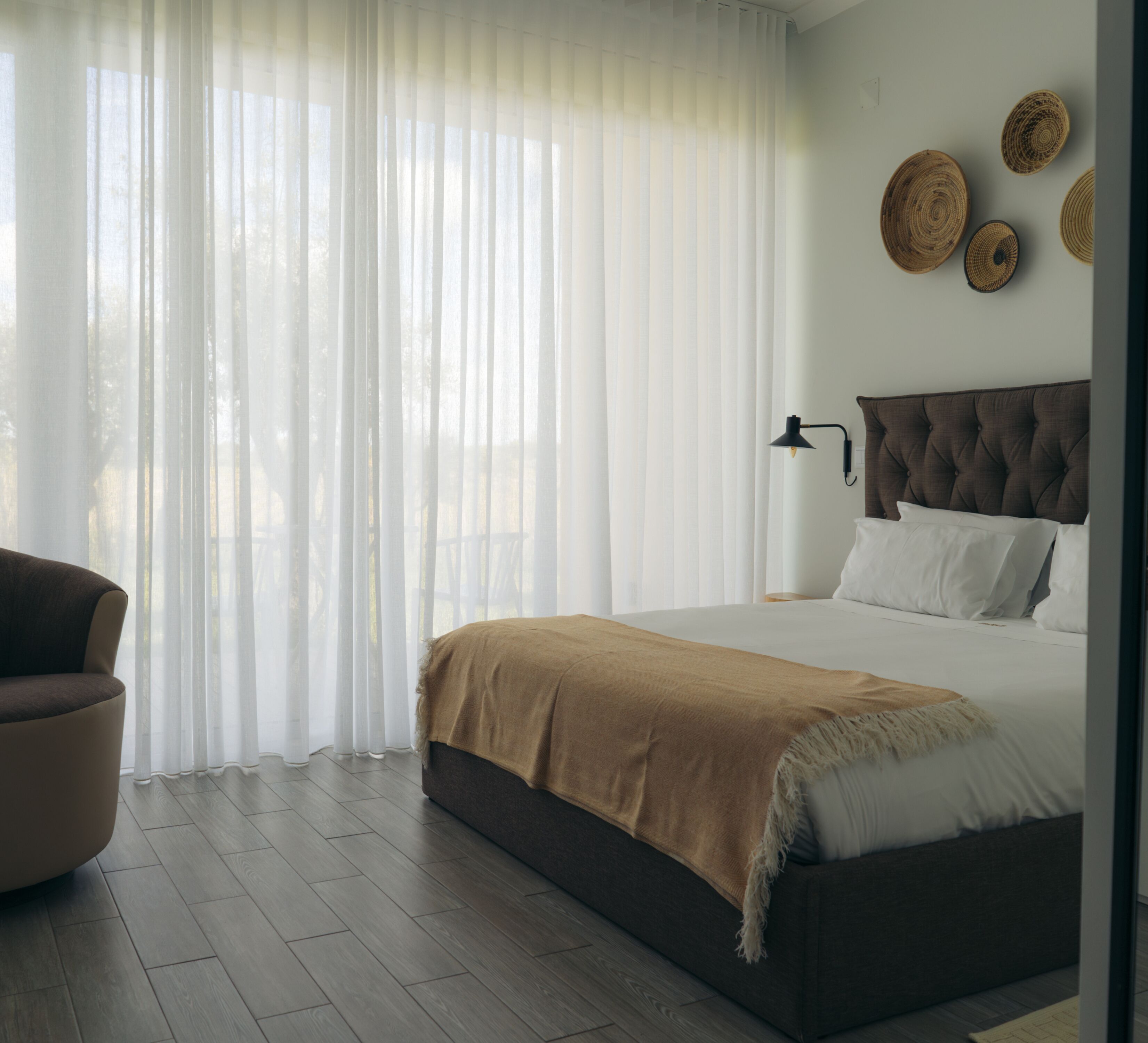 A bedroom with a bed, a chair, and a wall with decorative plates.