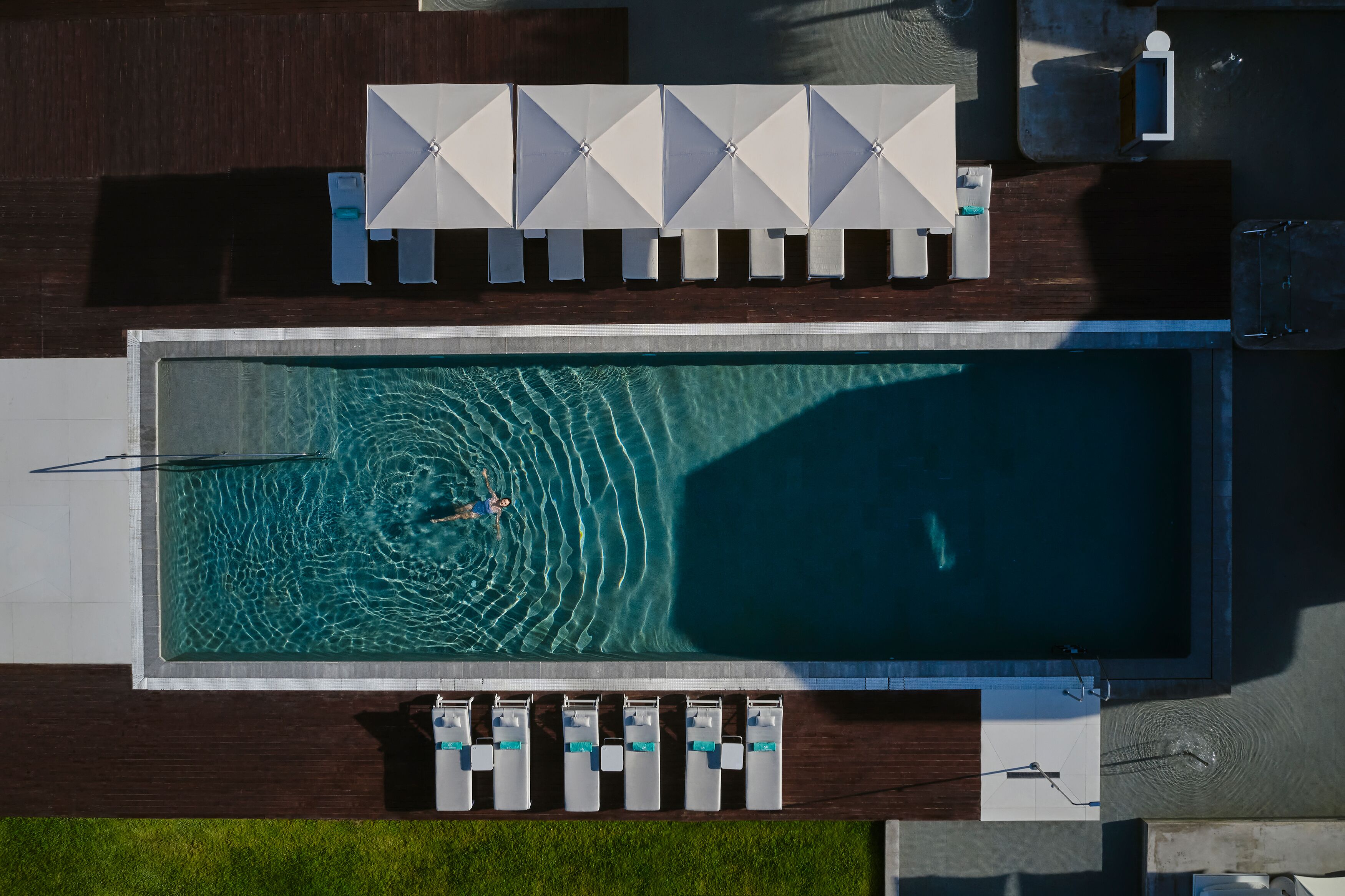 Vista aérea de una piscina con sillas de descanso y sombrillas.